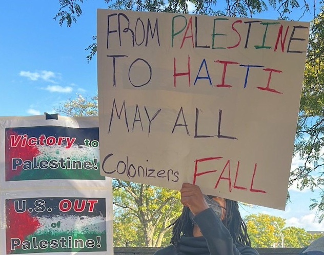 Protester holds a sign that reads - From Palestine to Haiti may all colonizers fail.x